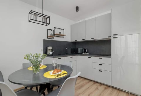 A closer look at the dining and kitchen area, featuring a round table set with elegant dishware, a black and white kitchen, and decorative lighting.

