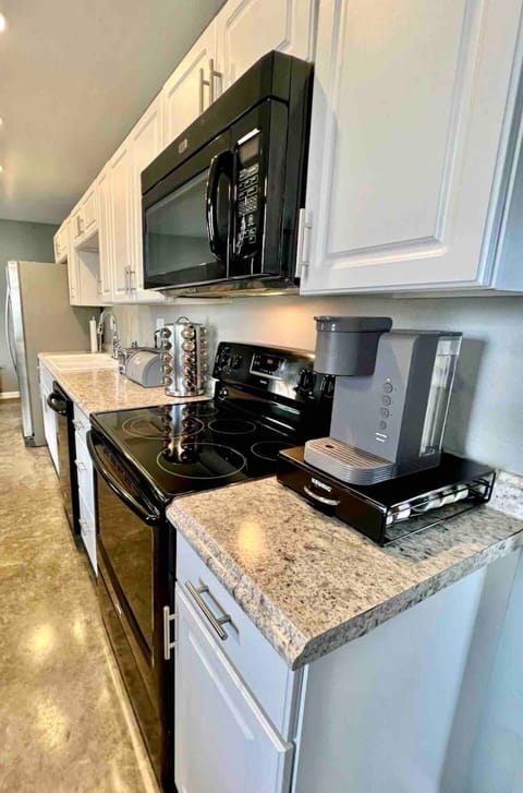 Long wall kitchen equipped with a full sized refrigerator, dishwasher, electric range/stove, and Keurig coffee maker. K cups are provided along with olive oil, and seasonings/herbs for cooking!