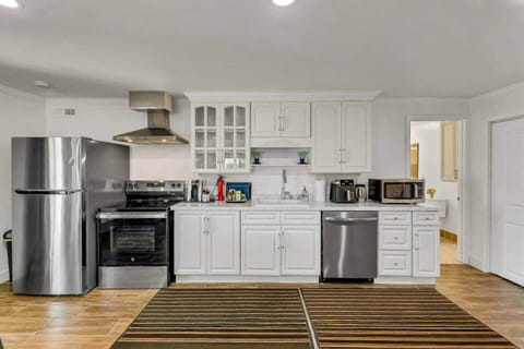 Full kitchen with new stainless steel appliances. Appliances include a refrigerator, electric stove and oven with hood, sink, dishwasher, microwave, Keurig coffee machine, hot water kettle, and air fryer. 