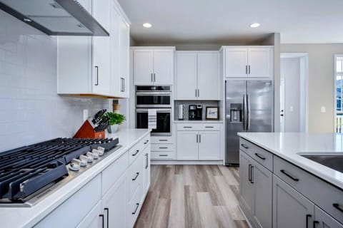 Experience culinary delights in our spacious, fully stocked kitchen featuring a sprawling island, gleaming stainless steel appliances, and a generously stocked pantry for all your cooking needs.