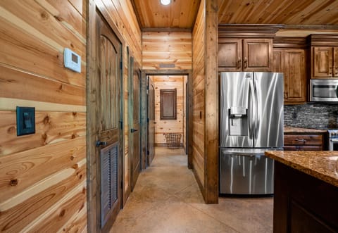 This kitchen corridor showcases the natural wood finishes of the walls and ceiling with a modern stainless-steel fridge situated at the side.