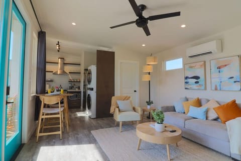 Bright and cozy South Austin casita with a remodeled kitchen, compact stacked washer/dryer, coastal-inspired decor, oak furniture, jute rug, and big glass doors letting in warm sunlight — your perfect winter retreat.