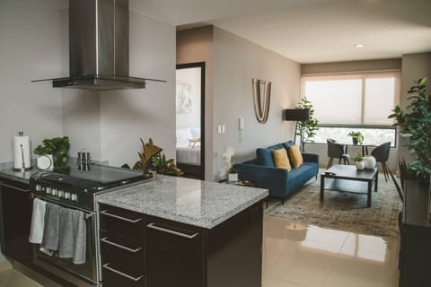 An inviting  living room bathed in abundant natural light, featuring a comfortable couch and an open-concept kitchen.