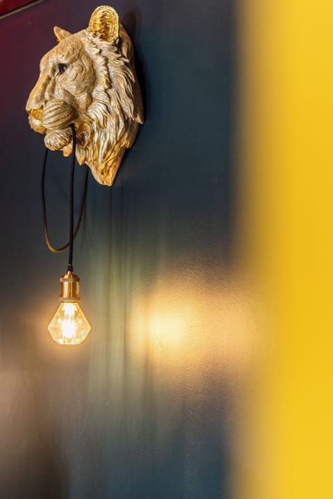 Side view of golden lion lamp casting warm light on a bold two-tone wall.