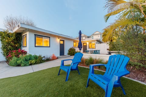Grassy backyard with blue Adirondack chairs and tropical landsca