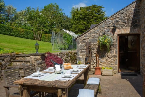 outside wooden garden table to seat 6 set with tablewear and wine, cushions for sitting