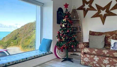 Sitting room with two seater sofa, window sea and stunning sea views and christmas decorations