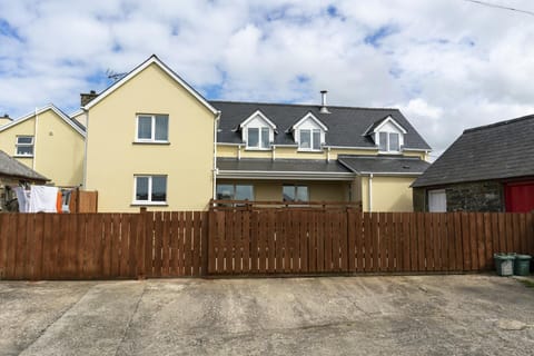 Cnwc Y Boidy. Brown wooden fence with front of cottage behind