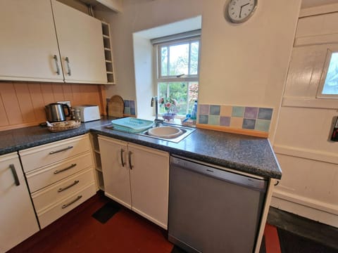 Kitchen with wall and base cupboards. Dishwasher and door leading to the garden