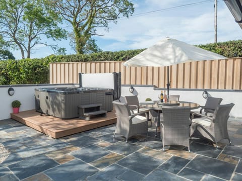 Hot tub, patio table, chairs and umbrella in the garden