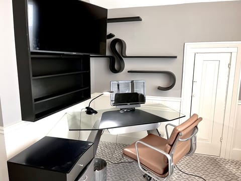 Glass desk, leather chair and TV extended from bookcase (monitor for scale only)