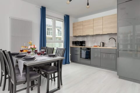 A modern dining area with a sleek table set for a meal, accompanied by wine glasses and fresh fruit.