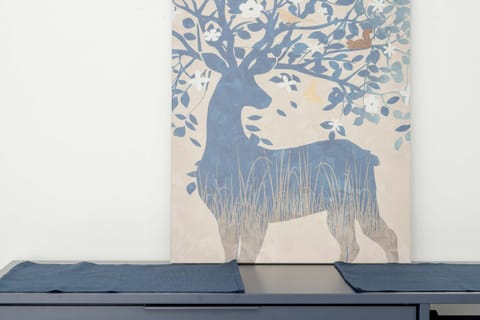 A unique wall art of a deer in a woodland setting, mounted above a stylish bench.
