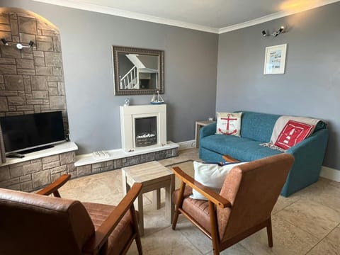 Sitting room with a two seater sofa, 2 armchairs and TV