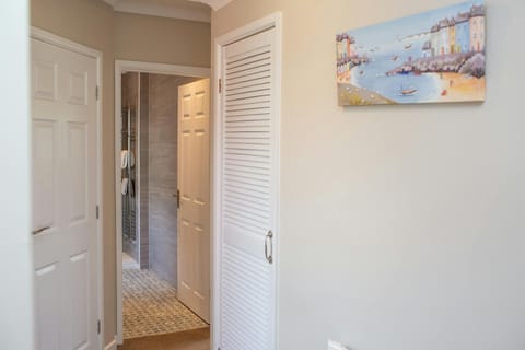 hallway leading to bathroom with wall art on wall of a seaside village