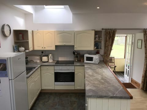 Kitchen with fridge, cooker, sink, doors into conservatory