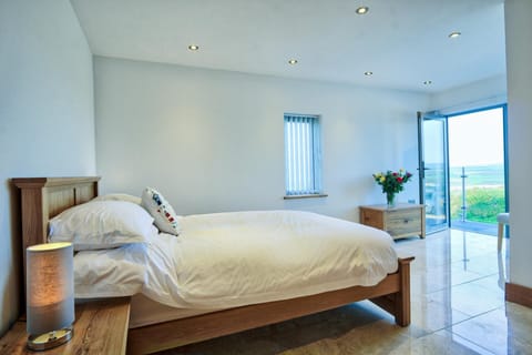 Ground floor bedroom with double bed and open patio doors to slate terrace, countryside beyond