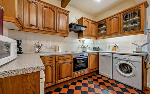 Kitchen with washing machine, oven and microwave. Pine wall and base units