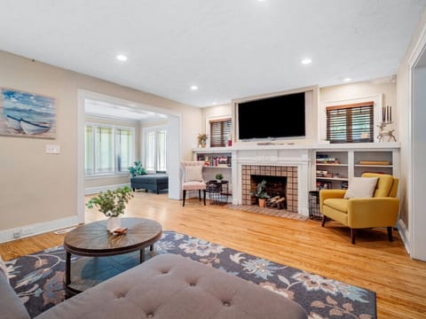 Bright and cozy living room with a comfy sectional 🛋️, floral rug 🌸, and a charming fireplace 🔥. Open layout flows into a stylish dining area — perfect for relaxing or entertaining 🍷✨.