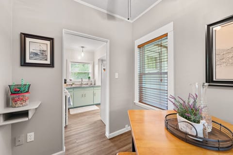 Compact galley kitchen features white appliances including a fridge and gas range under a microwave, paired with muted green cabinets and a double sink beneath a window. Bright and functional space 🍳🌿🔑