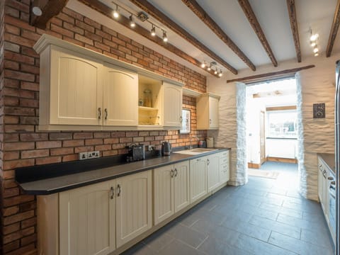 Kitchen cabinets on the wall and floor, sink and exposed beams on the ceiling