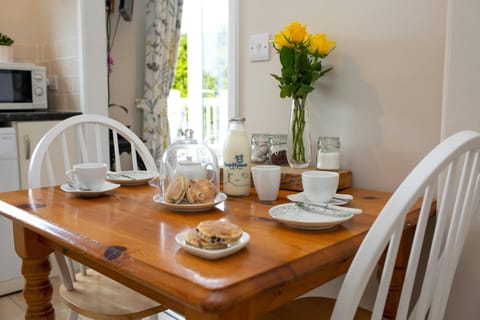 dining table dressed for dinner with welsh cakes and fresh milk, yellow roses in a vase