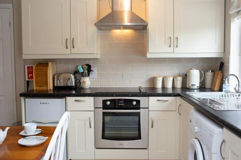 white cupboards and wall cupboards, toaster, kettle, oven and grill, hob and extractor fan