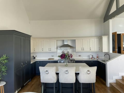 Open plan kitchen with breakfast bar island with bar stools and fresh flowers in vase