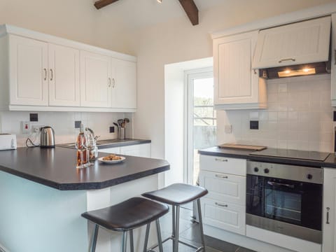 Kitchen area with breakfast bar and stools, cooker, sink