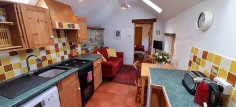 Kitchen area in Ty Gwennol, units, sink, cooker, toaster and kettle leading to living area