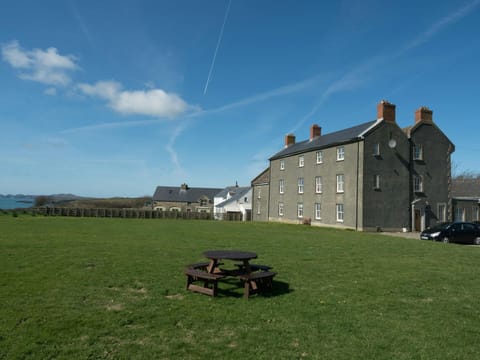 The outside of St Brides View with seating area on the lawn and sea views