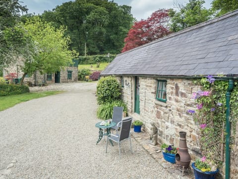 Cottage with gravel patio area with small table and chairs, surrounding trees