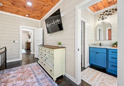 Stroll through the bright corridor adorned with a shabby chic dresser and an inviting bathroom entrance