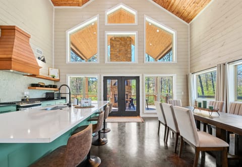 This area is highlighted by vibrant teal cabinets, a contrasting wooden range hood, and elegant white countertops