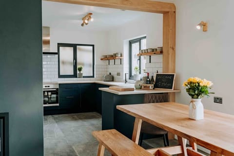 Ty Melyn No.2 Newgale – Stylish kitchen with wooden accents and a dining table set for six – complete with sea views from the window.