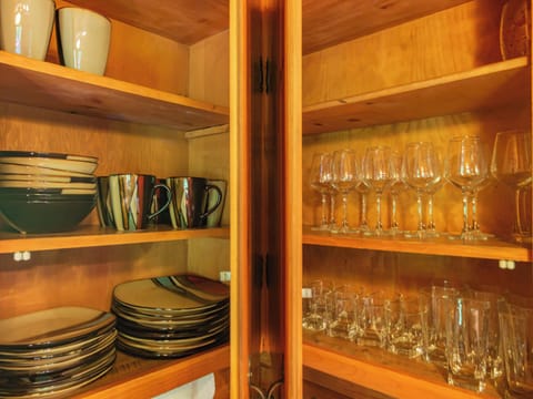 Plates, mugs, and drinking glasses are all in the cupboard.
