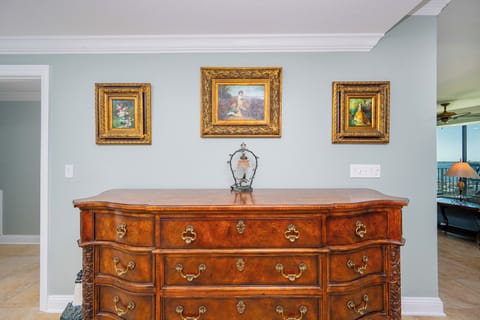 A wooden dresser with ornate details and framed artwork is displayed against a light blue wall in a stylish room