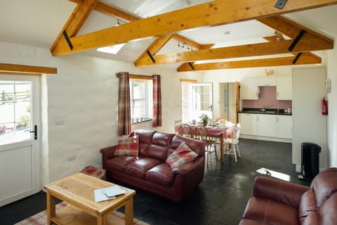 Open plan living room with leather sofas, coffee table, dining table, chairs and kitchen area