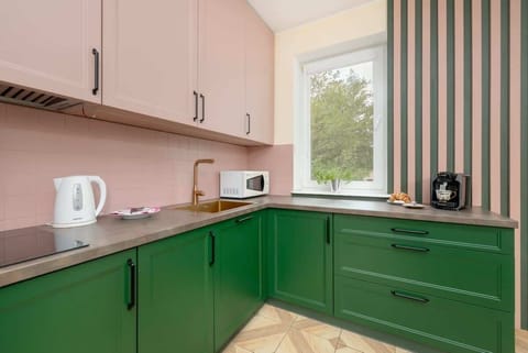 The pink and green kitchen stands out with its original colors and functional layout, making cooking enjoyable even during short stays.
