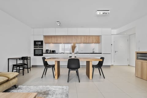 Step into a spacious, contemporary kitchen and dining area, featuring minimalist design and high-end appliances, ideal for both casual meals and gourmet cooking experiences.