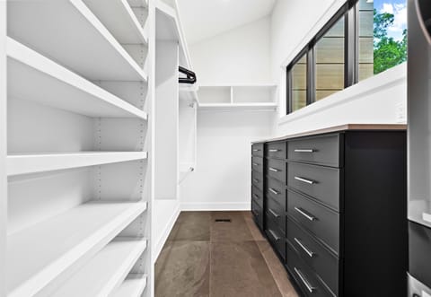 Enjoy a well-organized space with this spacious walk-in closet, featuring modern black cabinetry and efficient shelving.