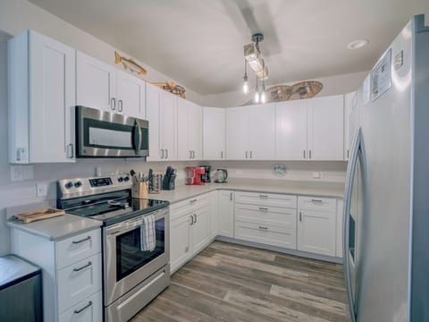 Bright kitchen with oven, microwave, kettle, and coffee maker—modern & cozy