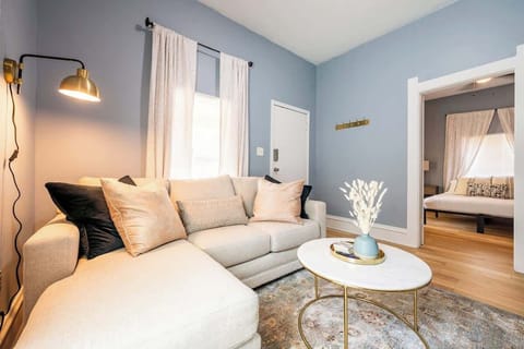 This cozy living room features a plush beige sectional sofa with accent pillows, and a modern marble-top coffee table with gold accents