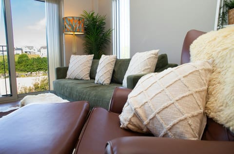 Living area with sofa, arm chair and foot stool with sheepskin throws and cusions