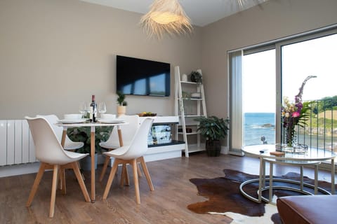 Dining area with table, four chairs and wall mounted TV. Patio doors with view