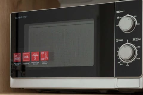 A close-up of a microwave oven with control knobs and safety stickers. Ready for quick meal prep or reheating snacks.