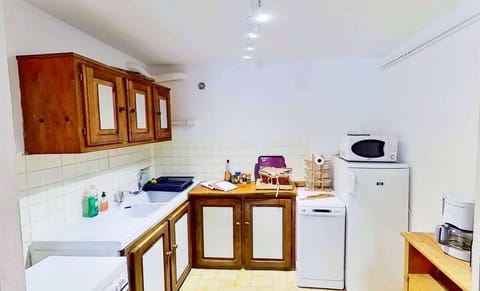 The kitchen is well-equipped with a dishwasher, microwave, oven, and refrigerator. There is ample storage space with wooden cabinets and a countertop that provides a convenient workspace. The kitchen is compact but functional and has everything you need t