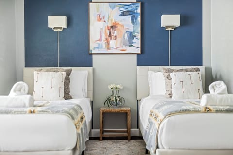 Bedroom 2 has 2 single beds with individual lamps on each wall board.