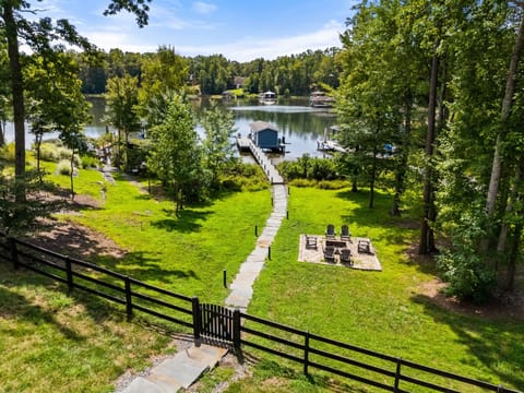 A picturesque lakefront property featuring a serene dock, lush greenery, and a cozy fire pit, perfect for relaxation and outdoor enjoyment.
