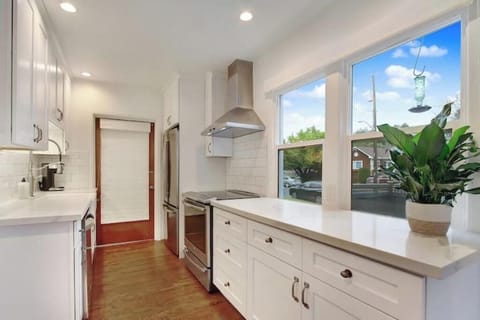 Galley kitchen with induction range, prep space, and access to utility room.